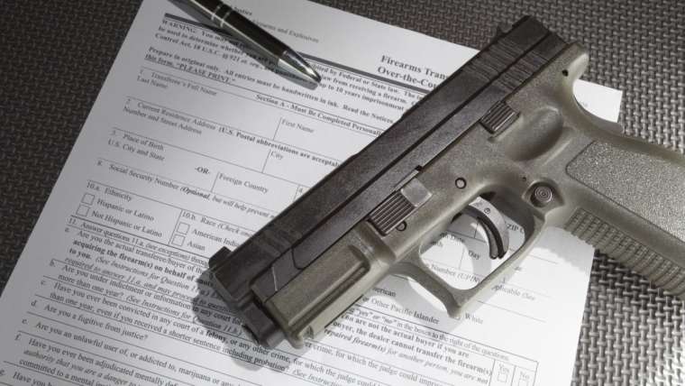 Handgun and pen on top of ATF Form 4473 - Firearm Transaction Record
