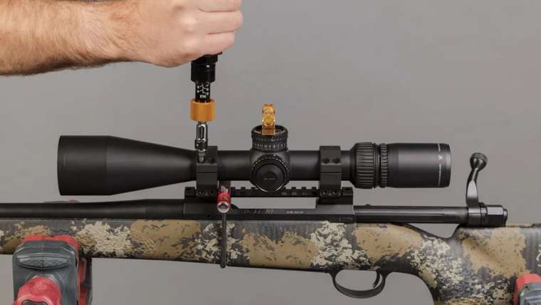 Male hand installing scope onto a bolt action rifle