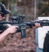 Man shooting AR-style rifle with sights and magnifiers properly mounted