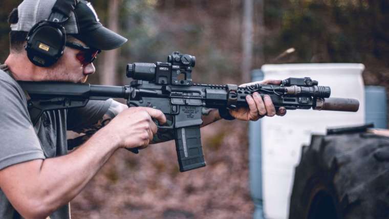 Man shooting AR-style rifle with sights and magnifiers properly mounted